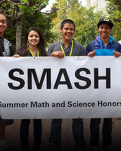 Group of students smiling behind a SMASH banner outside